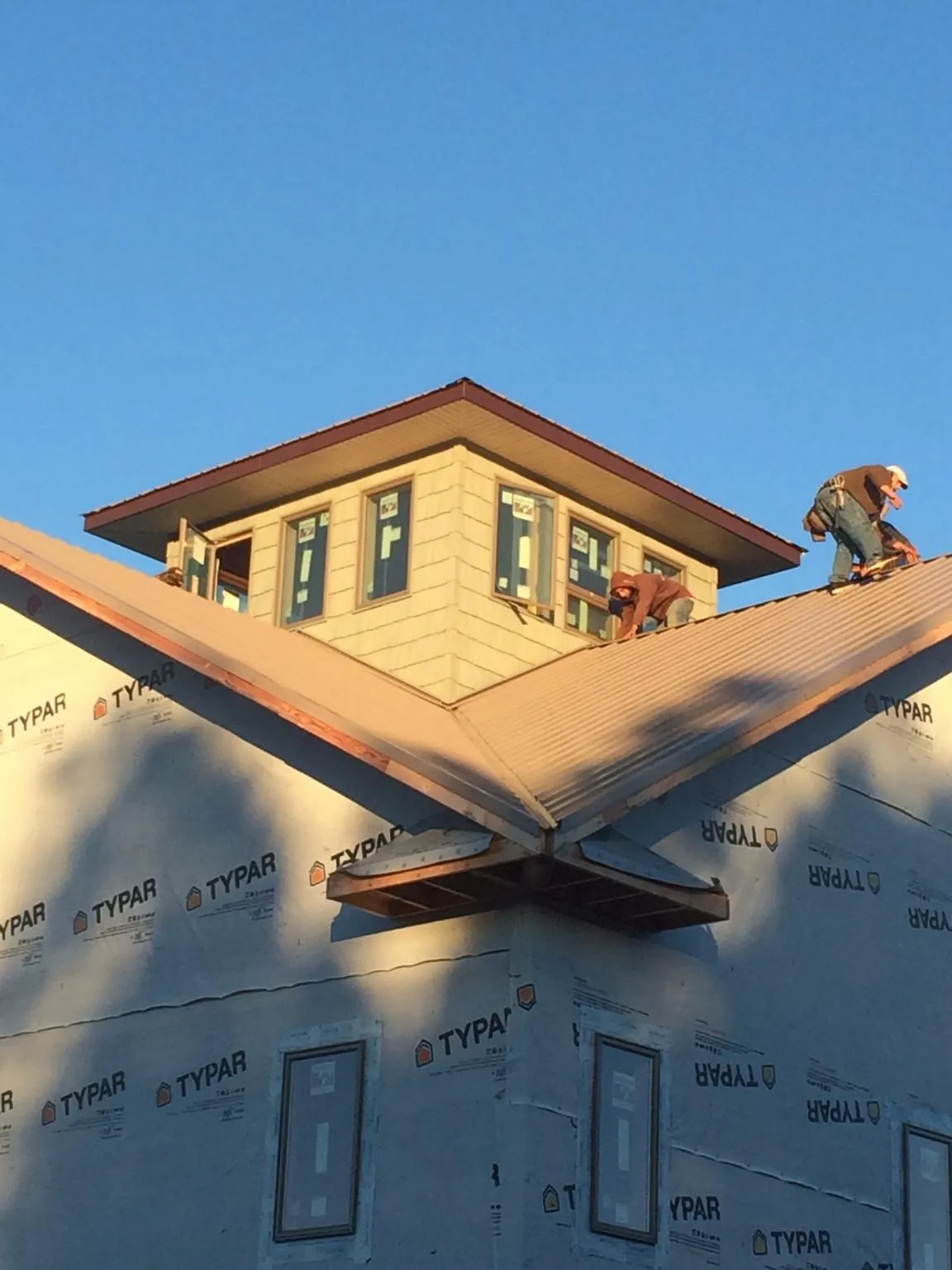 Roofers working around a rooftop cupola on a new metal roof at sunset — Roof Waterproofing in Corinth by Roofing Brothers